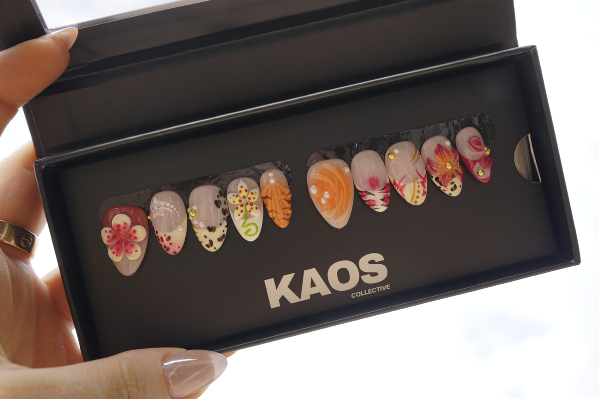 Box of colorful nail art designs with 'KAOS Collective' branding.
