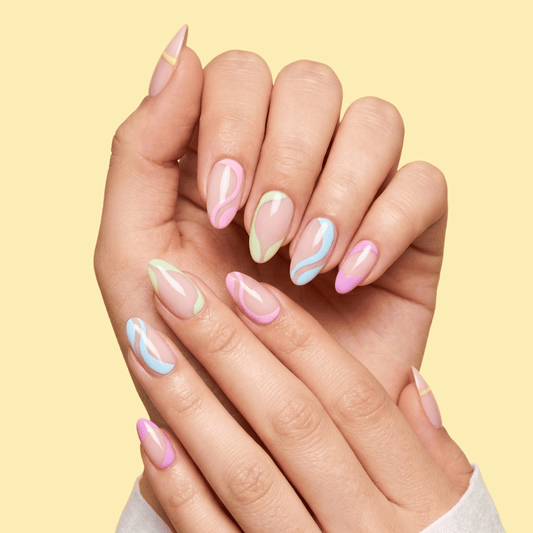 A close-up of 2 hands with manicured almond-shaped nails featuring pastel pink, mint green, and light blue marble swirl patterns, set against a solid pale yellow background.