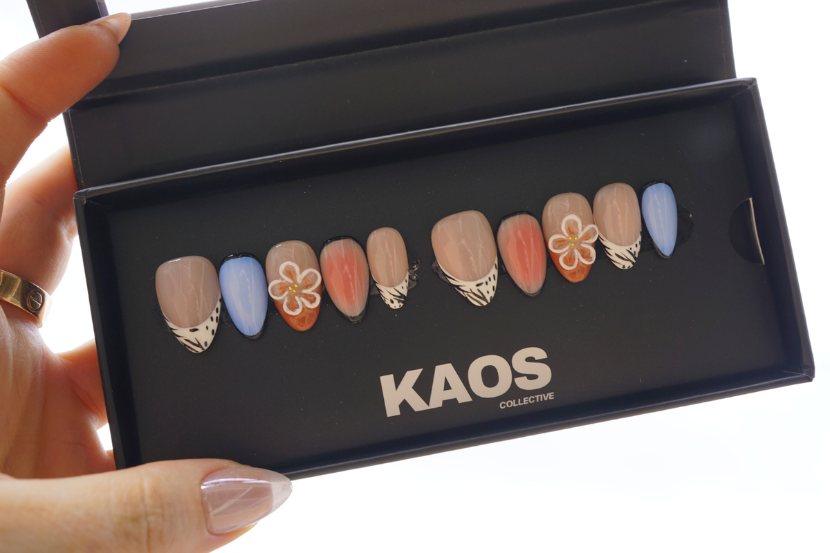 Nail art display with 'KAOS Collective' branding held by a hand.