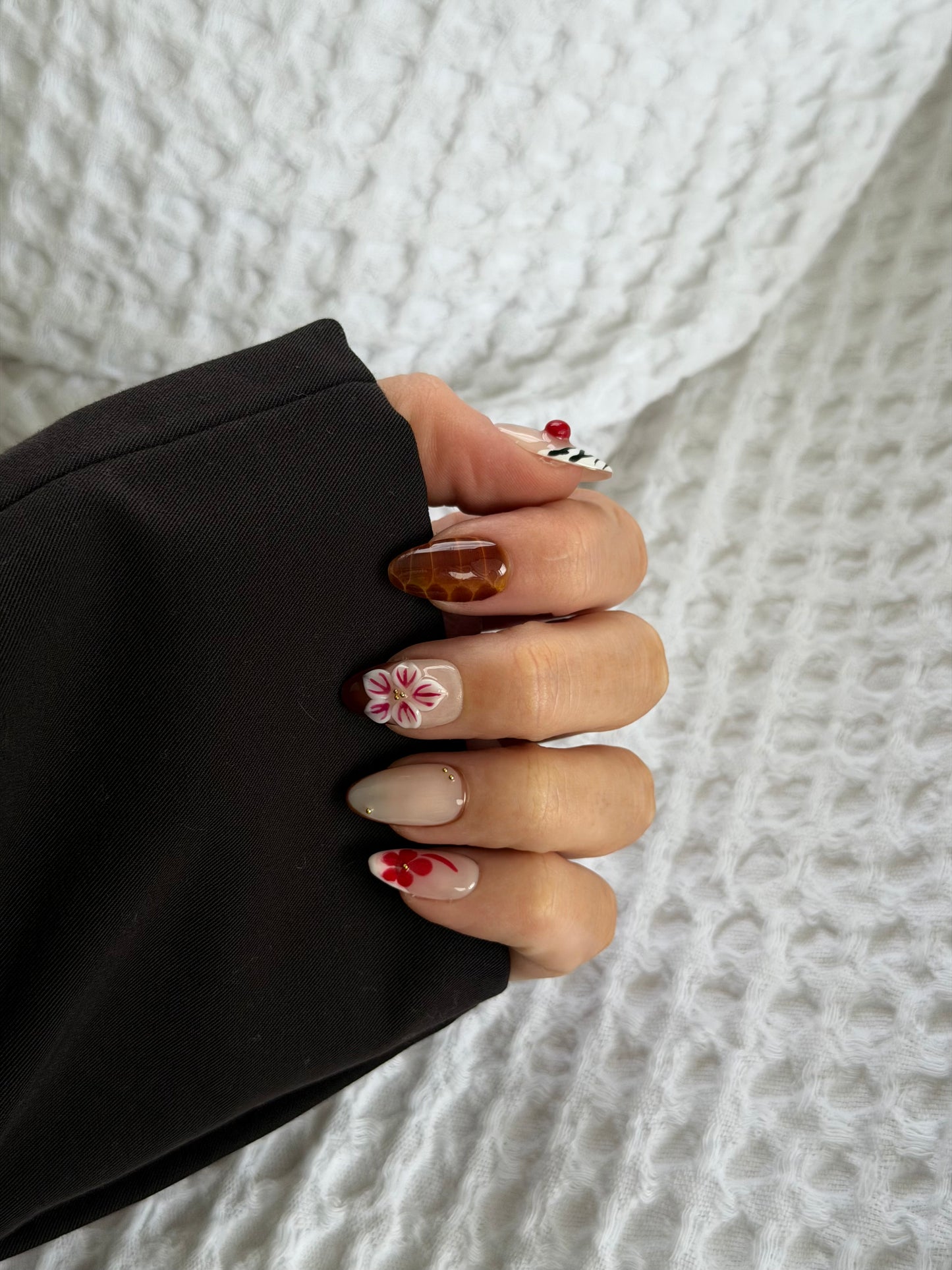 A hand wearing abstract press on nails on a white background
