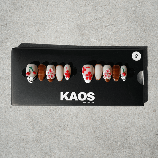 Set of decorative nails in a black box with 'KAOS Collective' branding on a gray background