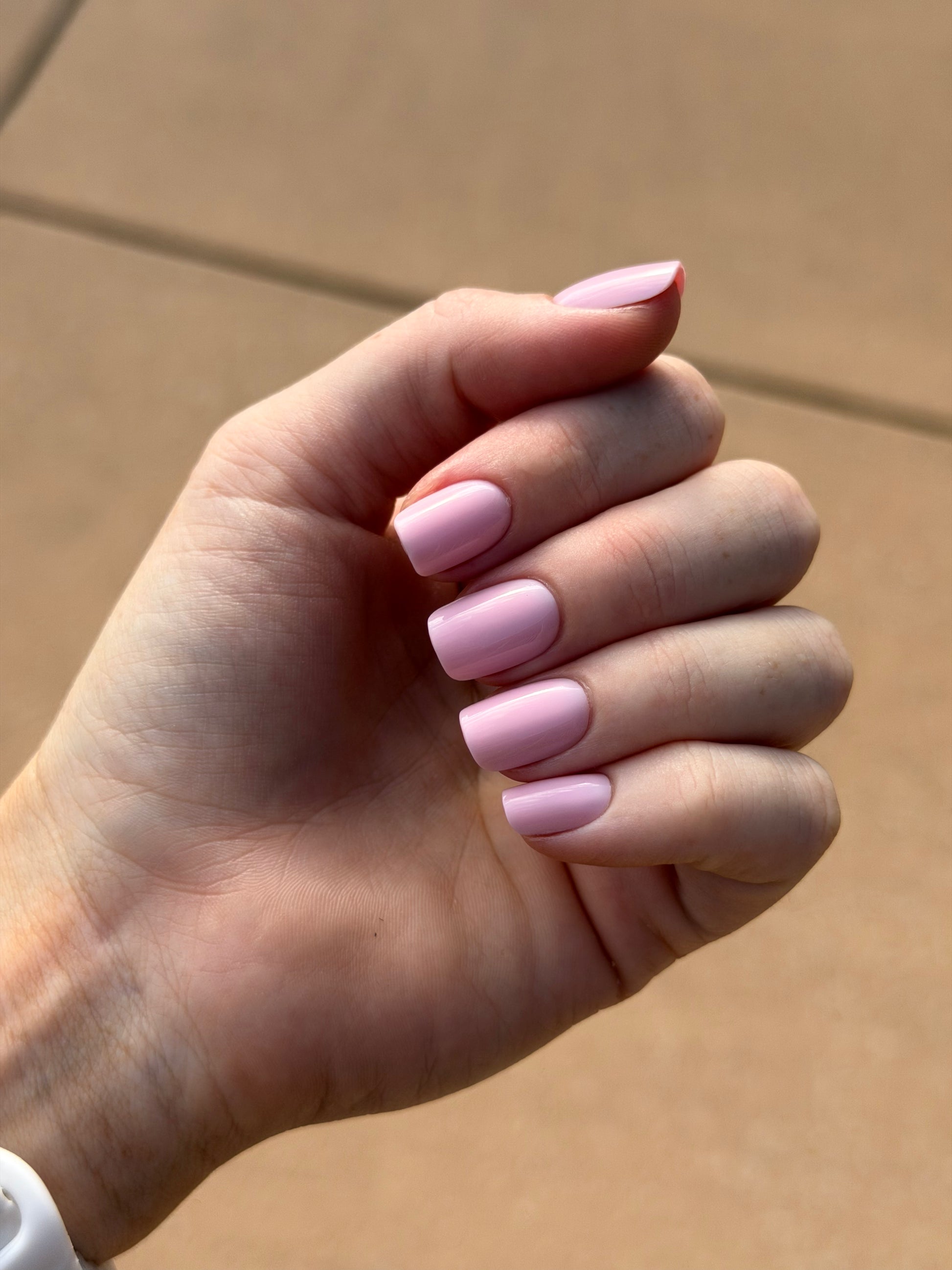 A hand wearing pink square press on nails