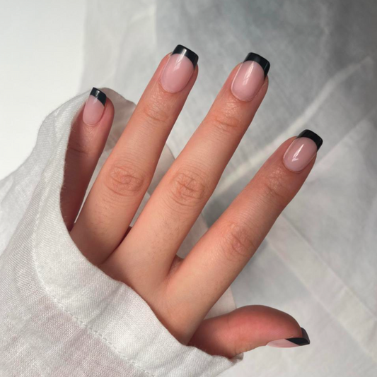 Hand with black and white nail design on a light background.