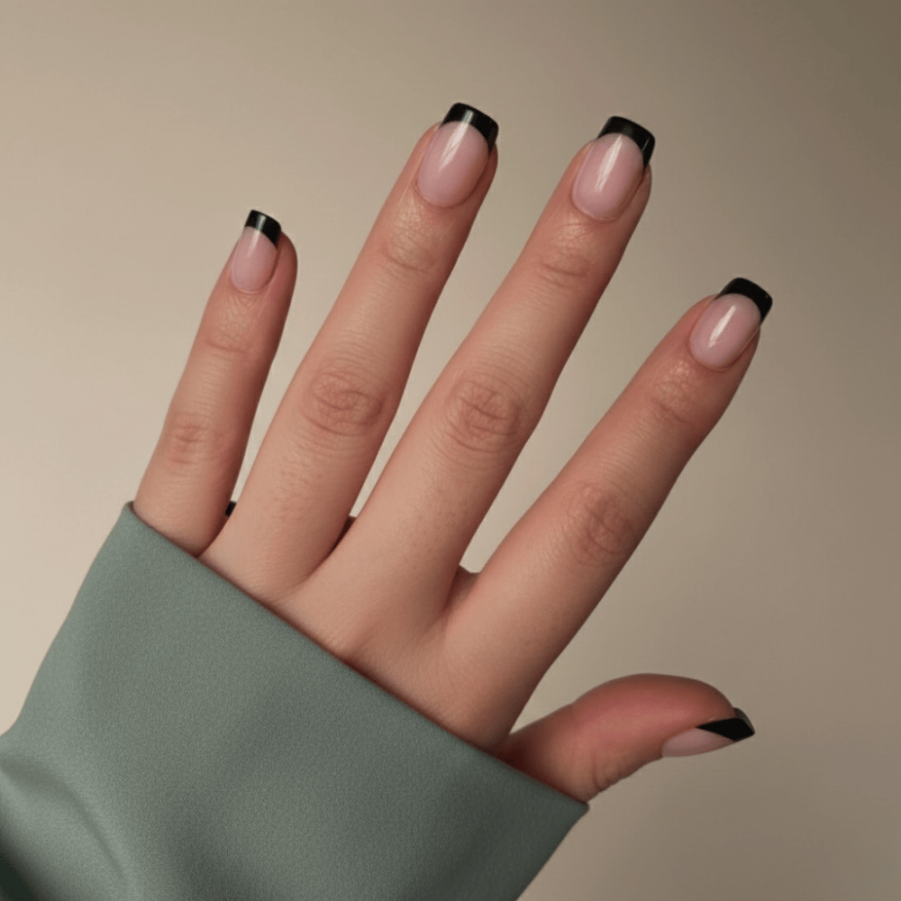 Hand with nails painted in a black and white design on a beige background