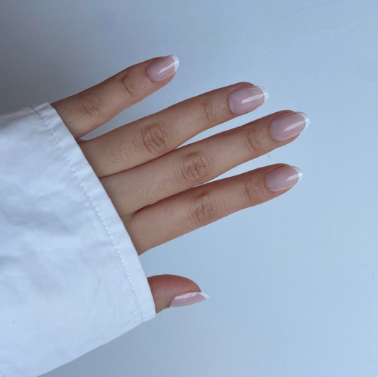 A hand with almond french tip press on nails on a light background