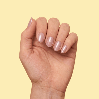 A close-up of a hand with manicured nails painted in a glossy, pale pink color, set against a solid pale yellow background.