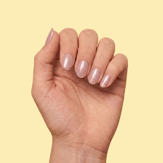 A close-up of a hand with manicured nails painted in a glossy, pale pink color, set against a solid pale yellow background.