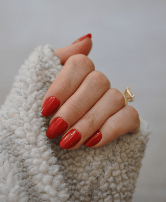 A person wearing red nails with a fluffy shirt