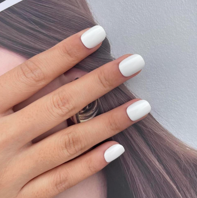 A set of white press on nails next to hair