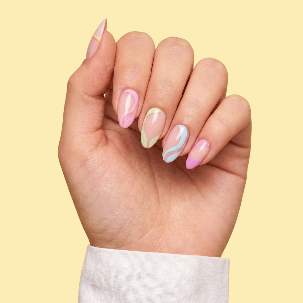 A close-up of a hand with manicured almond-shaped nails featuring pastel pink, mint green, and light blue marble swirl patterns, set against a solid pale yellow background.