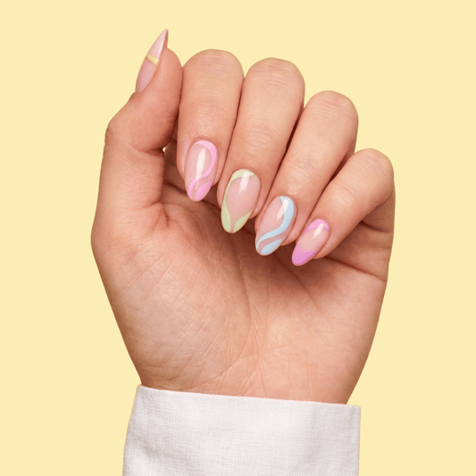 A close-up of a hand with manicured almond-shaped nails featuring pastel pink, mint green, and light blue marble swirl patterns, set against a solid pale yellow background.