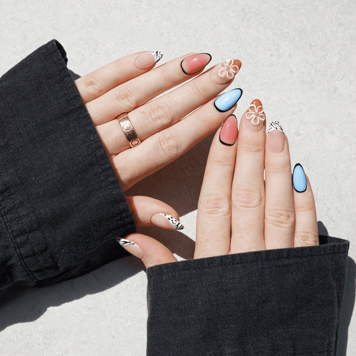 Close-up of hands with colourful press on nail designs on a light background