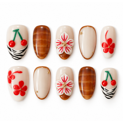 Ten almond-shaped press-on nails arranged in two rows on a white background. The nails feature glossy beige bases with various decorative designs including cherry motifs, red flowers, white cherry blossoms, brown wood-grain patterns, and small gold dot accents.