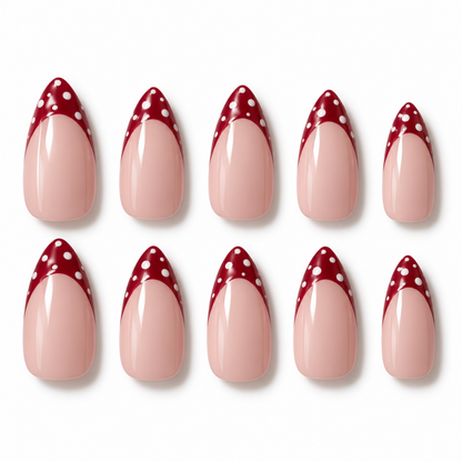Ten false almond-shaped nails arranged in two rows on a white background, featuring a glossy pale pink lower section and a deep red pointed tip with white polka dots.