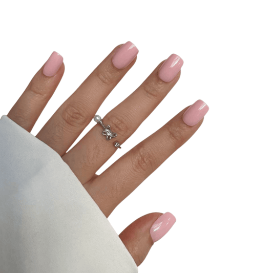 Hand with pink press on nails wearing a silver ring on a white background