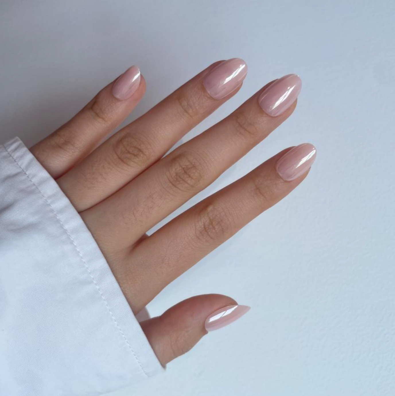 A hand with nude press on nails on a light background