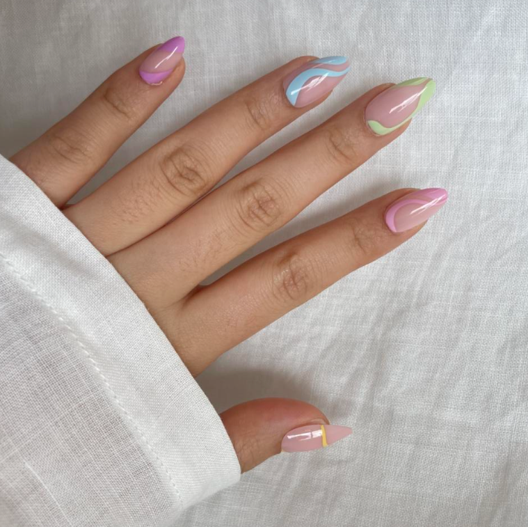 Hand with pastel press on nails on a light fabric background.