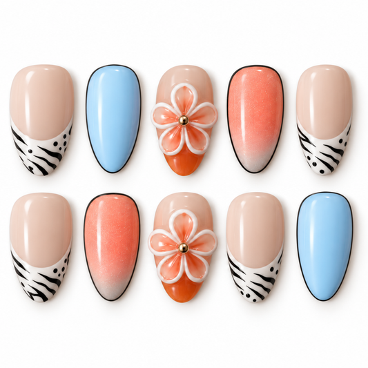 Ten artificial press-on nails arranged in two rows on a white background. The set includes nude beige nails with black-and-white zebra striping, light blue nails, peach-to-orange gradient nails, a 3D orange flower nail with white petals and a gold center, and one nude beige nail with a large orange flower on top.